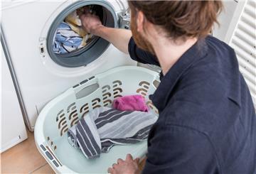 Eine Person packt Wäsche in die Waschmaschine.