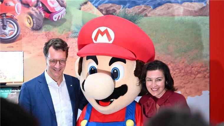 Mehr Games aus Deutschland? Branche bekommt staatliche Hilfe Beim Messerundgang über die Gamescom kam der Tross von Politikern auch beim Messestand von Nintendo vorbei, hier stehen NRW-Ministerpräsident Hendrik Wüst (CDU) und Bundesforschungsministerin Dorothee Bär (CSU) neben einer Mario-Plüschfigur.