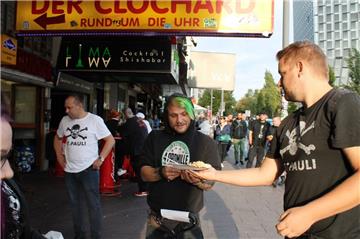 Benjamin Haxel (rechts) verteilt auf der Reeperbahn in Hamburg Schnitzel mit Nudelsalat an bedürftige Menschen.