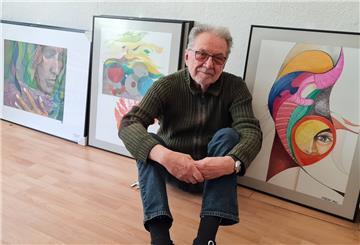 Ein Mann sitzt vor Kunstwerken