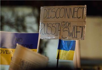 Berlin: "Disconnect Russia from Swift" steht auf einem Transparent, das eine Person während der Mahnwache zum Ukraine-Konflikt vor der Russischen Botschaft hält.