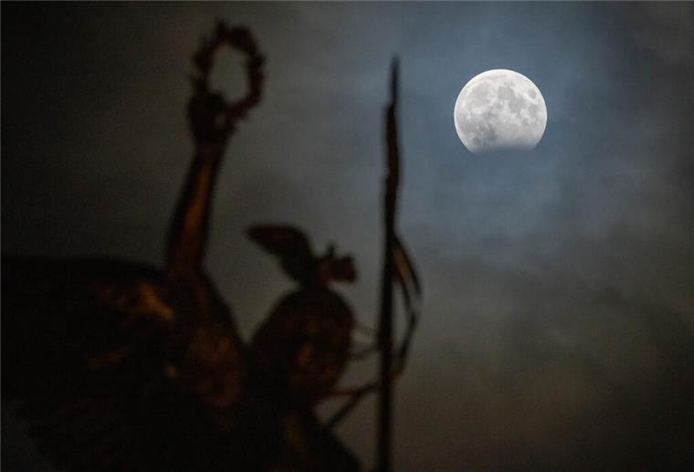 Berlin: Hinter der Goldelse auf der Siegessäule ist eine partielle Mondfinsternis zu sehen.