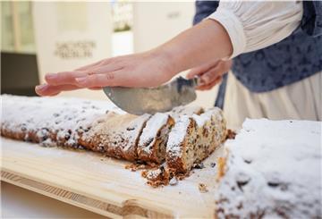 Eine Frau schneidet einen Stollen an.
