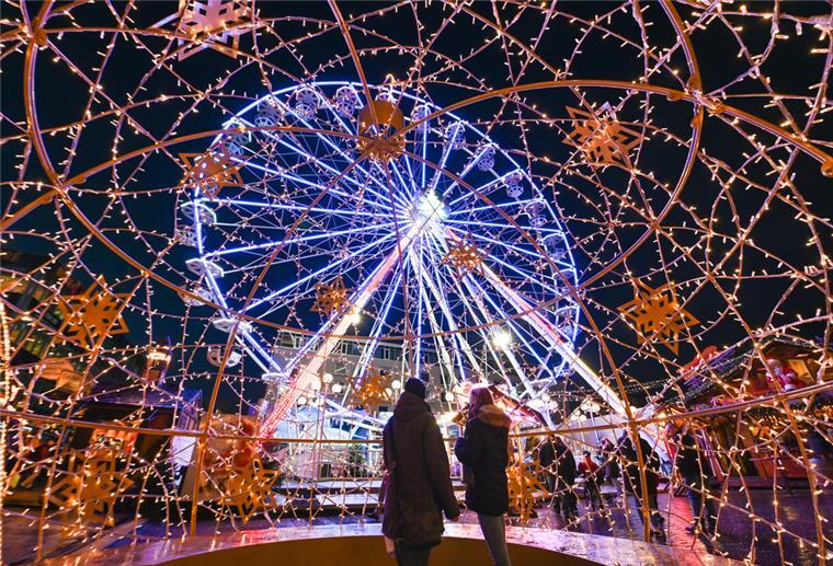 Auf dem Bremerhavener Weihnachtsmarkt dreht sich das leuchtende Riesenrad im Dunkeln.