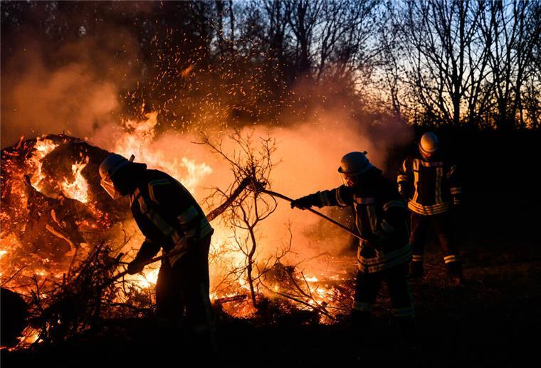 Feuerwehrkräfte schichten ein Osterfeuer auf.