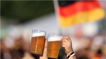 Bierbecher werden in die Höhe gehalten, im Hintergrund weht eine Deutschland-Flagge.
