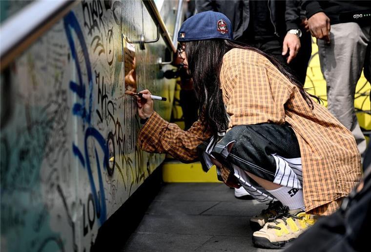Billie Eilish feiert die vegane Gastronomie in Berlin Billie Eilish signiert auf der „Billie Eilish-Wand“.