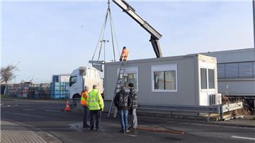 Männer stehen vor einem Baucontainer.