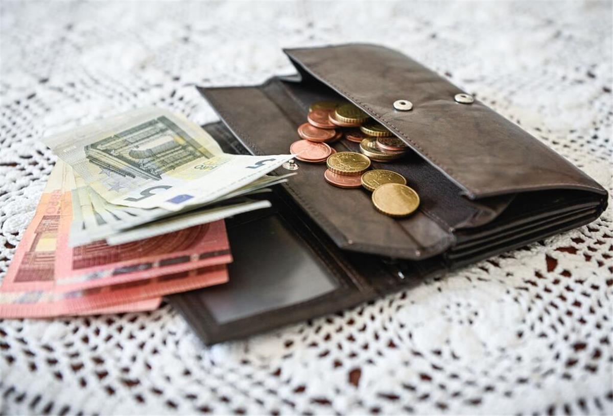 Merz-Regierung streicht zugesagte 200-Euro-Hilfe! Millionen Bürger betroffen Eine Geldbörse liegt auf einem Tisch.