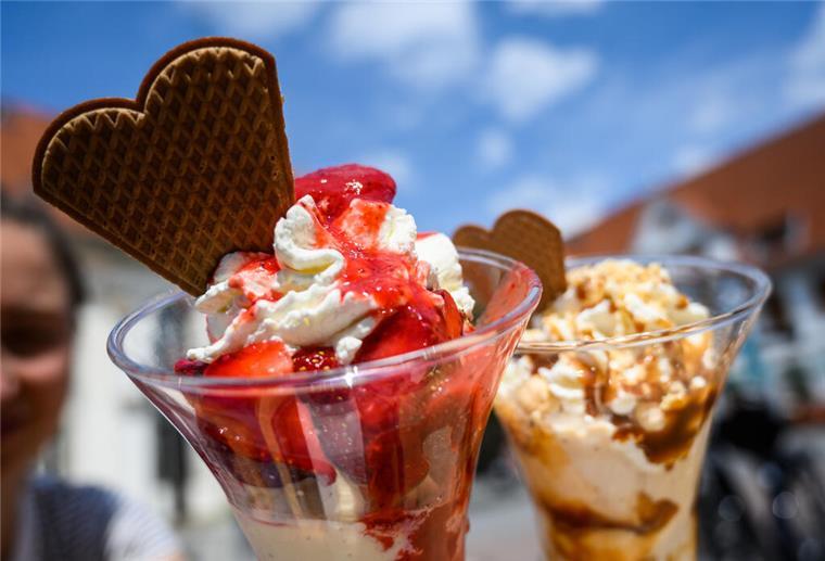 Zwei Eisbecher stehen auf einem Tisch am Marktplatz vor blauem Himmel.