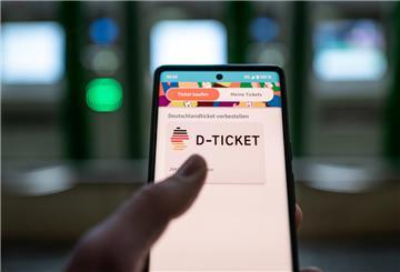 Ein Mann hält ein Mobiltelefon, auf dem das ·D-Ticket· gekauft werden kann