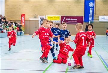 Kinder spielen Fußball in einer Halle.
