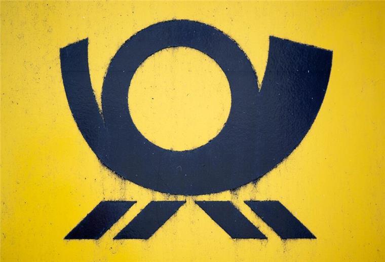 Blick auf einen Briefkasten der Deutschen Post, auf dem das Posthorn-Logo zu sehen ist.