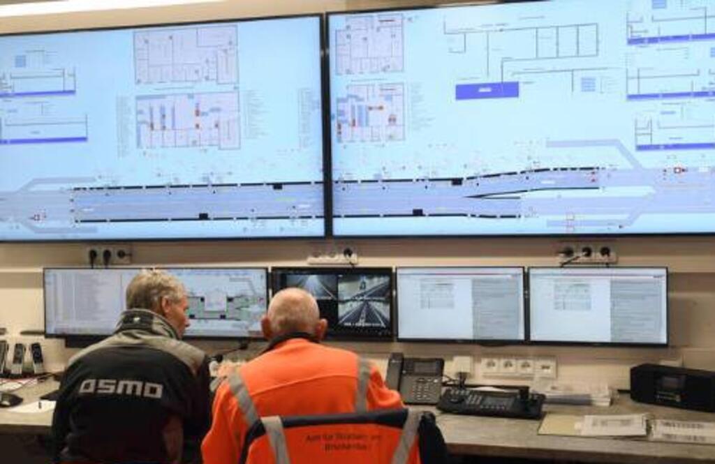 Zwei Männer sitzen vor vielen Monitoren.