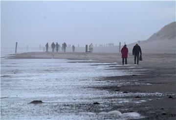  Niedersachsen, Norderney: Spaziergänger sind am Weststrand der Nordsee-Insel unterwegs.
