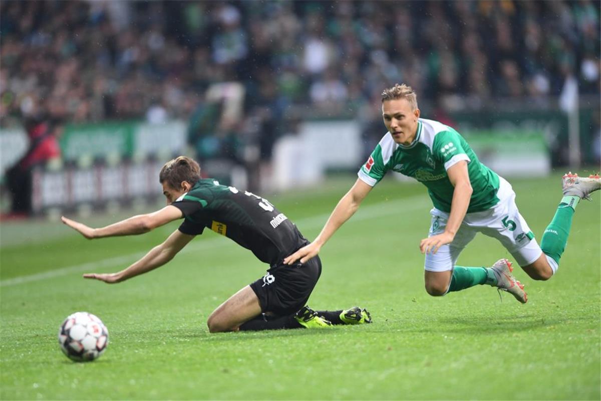 Bremens Ludwig Augustinsson (rechts) und Gladbachs Michael Lang fallen nach einem Zweikampf auf den Rasen. 