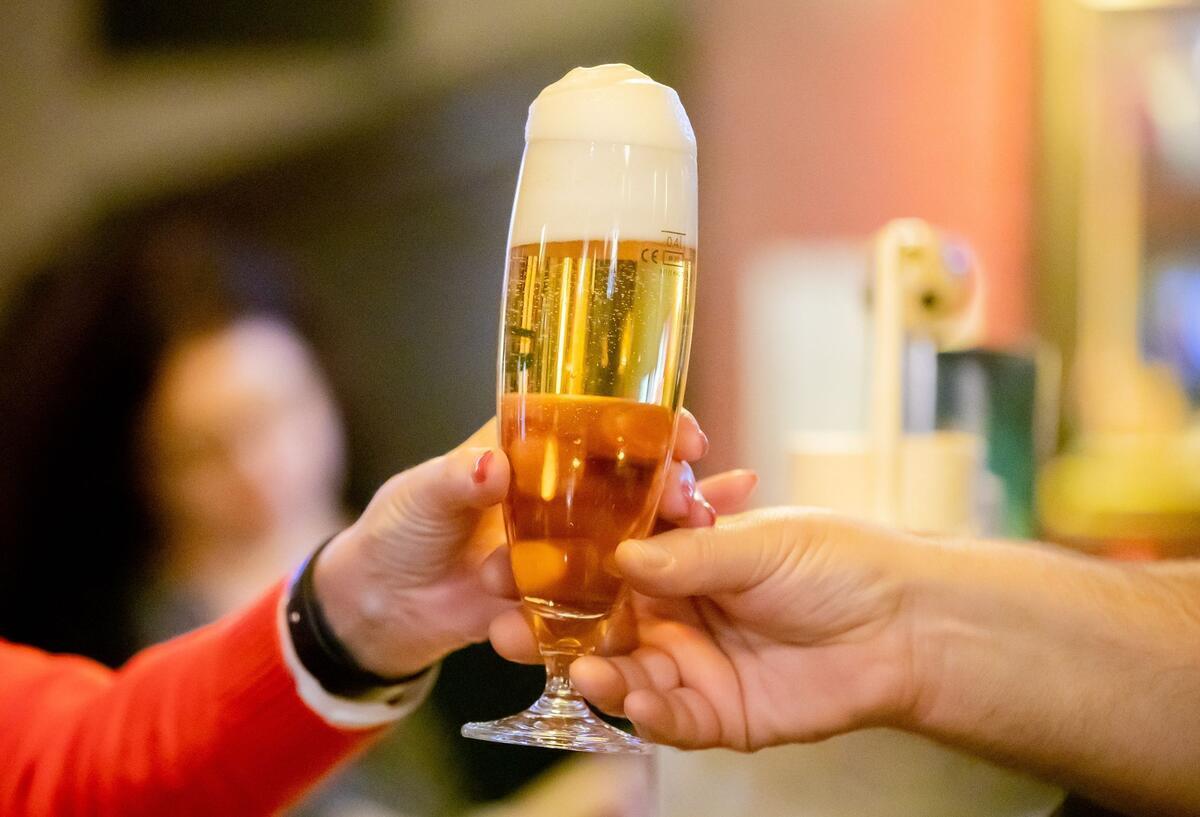 Eine Person reicht einer anderen Person ein Bier.