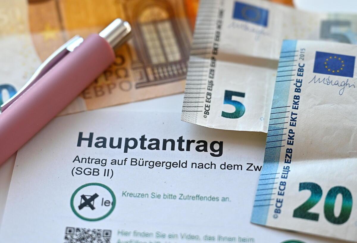 Alle Bürgergeld-Empfänger betroffen! Härtere Strafen für Pflichtverstöße geplant Der Hauptantrag für Bürgergeld liegt neben Geldscheinen auf einem Tisch.