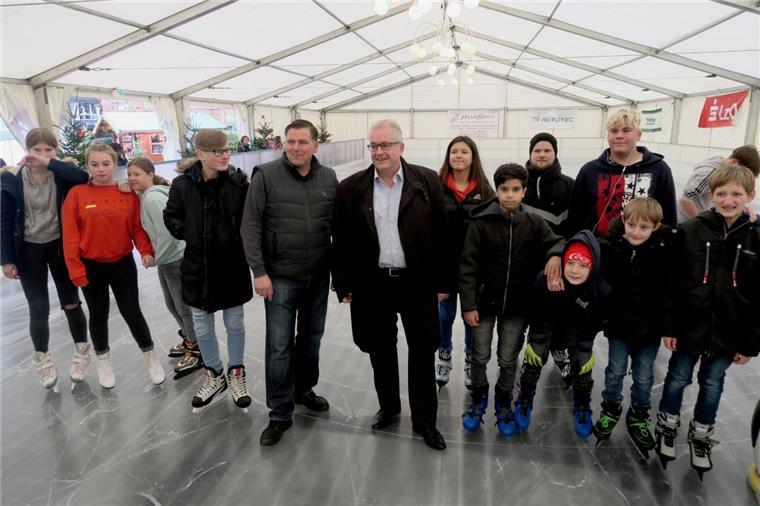 Bürgermeister Carsten Seyfarth (Mitte, helles Hemd) und Veranstalter Peter Böseler freuen sich mit den ersten Gästen darüber, dass in Nordenham auch in diesem Winter ein Eiszelt auf dem Marktplatz steht. 