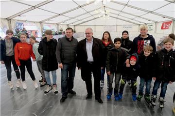 Bürgermeister Carsten Seyfarth (Mitte, helles Hemd) und Veranstalter Peter Böseler freuen sich mit den ersten Gästen darüber, dass in Nordenham auch in diesem Winter ein Eiszelt auf dem Marktplatz steht. 