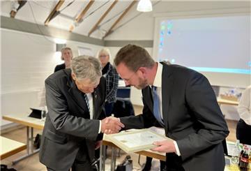 Zwei Männer in grauen Anzügen schütteln sich die Hände und verbeugen sich voreinander.