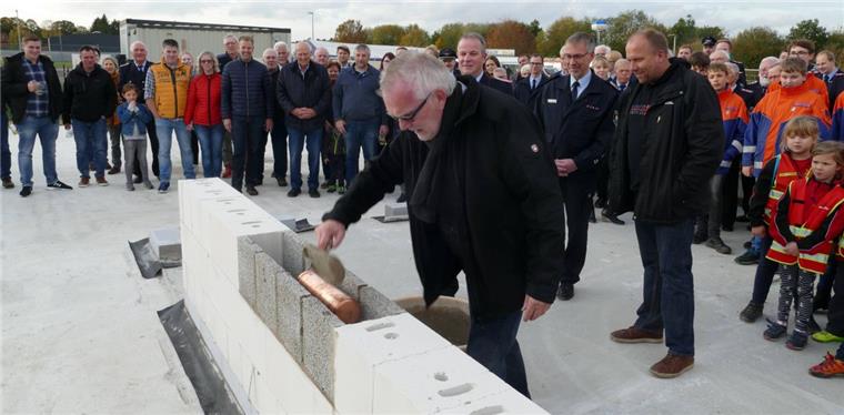 Bürgermeister Ulf Voigts mauerte eine Kupferhülse mit Plänen und der aktuellen NORDSEE-ZEITUNG in Lunestedt ein.