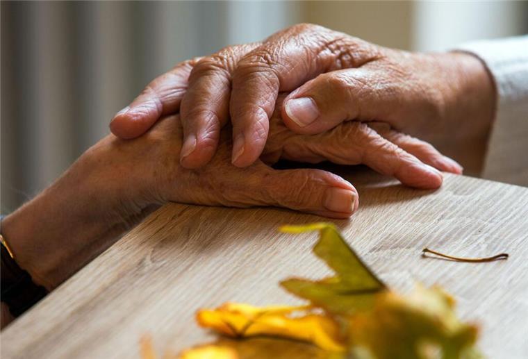 Pflege zu Hause: Regierung fordert finanzielle Unterstützung für Angehörige Zwei ältere Menschen halten sich an der Hand.