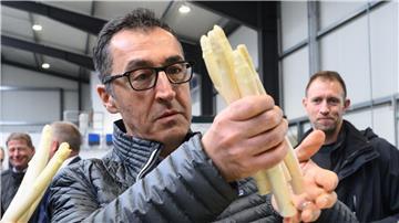 Bundeslandwirtschaftsminister Cem Özdemir (Grüne) hält Spargel bei einem Besuch vom Spargelhof Heuer in der Region Hannover.