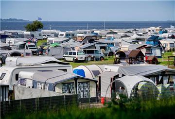 Wohnwagen und Wohnmobile stehen bei sonnigem Wetter auf einem Campingplatz