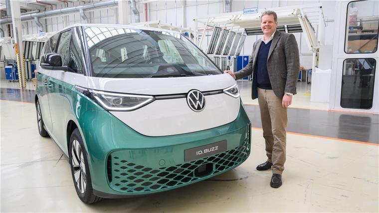 Carsten Intra, Vorstand Volkswagen Nutzfahrzeuge, steht neben einem Elektrobus Volkswagen ID.Buzz im Werk von Volkswagen Nutzfahrzeuge in Hannover.