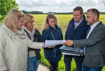 Chiara Bürgerhoff, Lisa Witting, Ricarda Kathen und Lukas Haack (v. li.) gehören zu der Gruppe von jungen Leuten, die in Bramel bauen wollen. IDB-Prokurist Alexander Thorau zeigt ihnen die Pläne des Geländes hinter ihnen. Foto Scheschonka