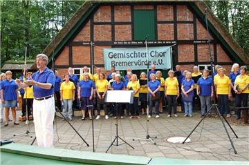Chorleiter Dr. Hans-Martin Kallenberger und die mehr als 30 Mitglieder des Ensembles fordern das Publikum zum Mitsingen auf.  