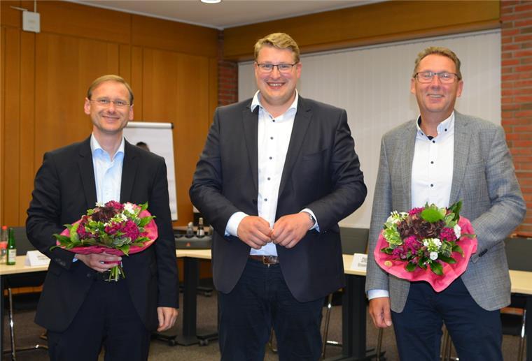 Schiffdorf: Wechsel an der Verwaltungsspitze Drei Männer stehen in einem Raum, zwei mit Blumen in der Hand.