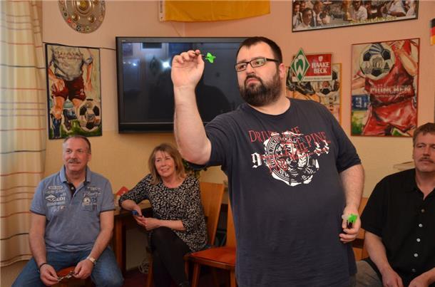 Christian Kuhl konzentriert sich beim Werfen. Henry Kruse, Silvia Schomburg und Holger „Slow Hand“ Schütt schauen zu.