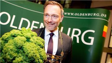 Christian Lindner (FDP), Bundesfinanzminister, trägt eine Kohlkette und hält eine Grünkohlpflanze, auch bekannt als „Oldenburger Palme“, in den Händen.