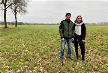 Vater und Tochter stehen nebeneinander auf einem mit Gras bewachsenen Acker.