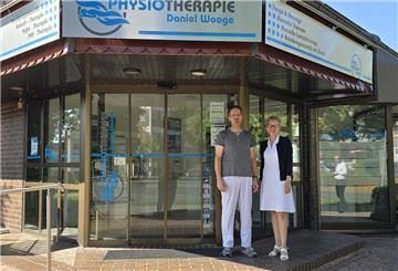 Christiane Thürlings, Vorstand der Raiffeisenbank, und Physiotherapeut Daniel Wooge stehen vor dem Praxisgebäude. 