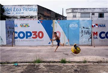ARCHIV - 23.03.2025, Brasilien, Belem: Ein Junge kickt einen Fußball in der Nähe der Beschilderung für die UN-Klimakonferenz COP30 in Belem, Brasilien. (zu dpa: «Brasilien chartert Kreuzfahrtschiffe als Hotels für COP30») Foto: Jorge Saenz/AP/dpa +++ dpa-Bildfunk +++