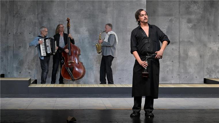 Da landet der Wein im eigenen Mund: Henning Bäcker als Plietschmann, im Hintergrund spielt die Band (Jan-Hendrik Ehlers, Stephan Werner, Marco Priedöhl).