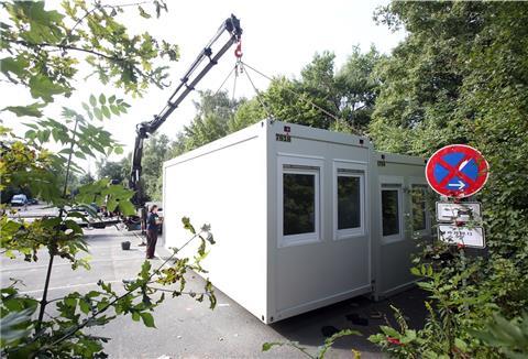 Arbeiter stellen Wohncontainer auf.
