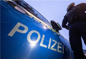 Eine Polizistin steht neben einem Polizeifahrzeug.