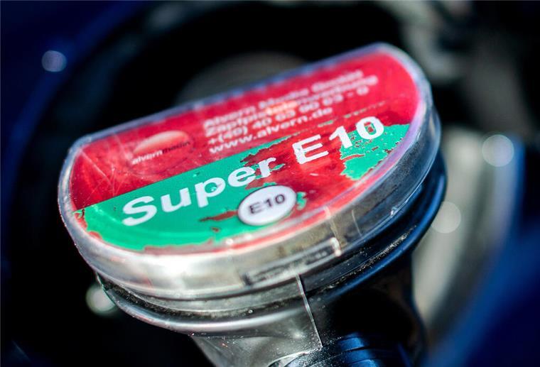 Ein Zapfhahn trägt die Aufschrift E10 und hängt in einem Auto. Um den günstigen Sprit gibt es viele Vorurteile.