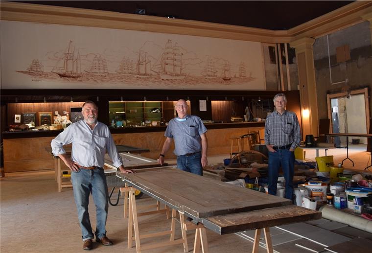Das Bild über der Bar ist bislang während der Bauarbeiten im Kinosaal verhängt gewesen, damit es keinen Schaden erleidet. Jetzt freuen sich Jan Kuilert, Norbert Ostendorf und Jens Frost (von links), dass die Schutzmaßnahmen Erfolg hatten.