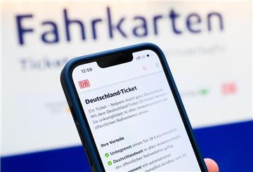  Eine Person hält am Hauptbahnhof ein Smartphone in der Hand, auf dessen Display eine Information zum Kauf des Deutschlandtickets zu sehen ist, während sie vor einem Fahrkartenautomaten steht