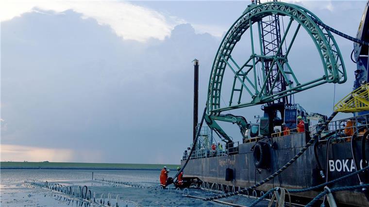 Das Endstück eines 516 Kilometer langen Seekabels für die Stromleitung Nordlink zwischen Deutschland und Norwegen wird von dem Kabelverlegeschiff „Boka Connector“ im Watt unter dem Deich hindurch an Land gezogen. Auch zwischen Deutschland und Großbritannien ist eine „Stromautobahn“ unter Wasser geplant.