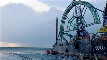 Das Endstück eines 516 Kilometer langen Seekabels für die Stromleitung Nordlink zwischen Deutschland und Norwegen wird von dem Kabelverlegeschiff „Boka Connector“ im Watt unter dem Deich hindurch an Land gezogen. Auch zwischen Deutschland und Großbritannien ist eine „Stromautobahn“ unter Wasser geplant.