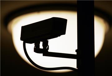 Eine Video-Überwachungskamera zeichnet sich vor einer Lampe in einem S- und U-Bahnhof als dunkle Silhouette ab.