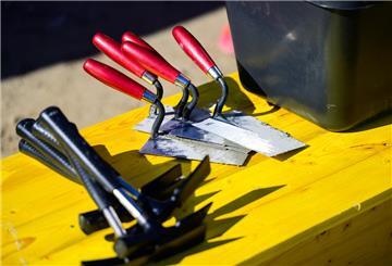 Maurerhammer und Maurerkellen liegen auf einer Baustelle.