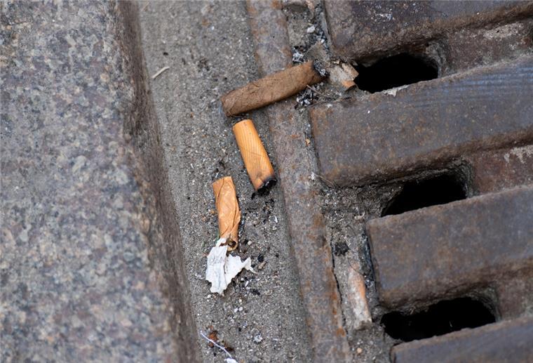 Diese Bußgelder erwarten Müllsünder in Bremerhaven und Bremen Zigarettenkippen liegen auf der Straße an einem Kanaldeckel. Hamburgs Waste-Watcher.