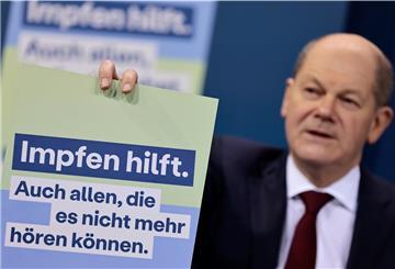 Bundeskanzler Olaf Scholz (SPD) präsentiert ein Plakat für eine neue Impfkampagne während einer Pressekonferenz nach einem Treffen.